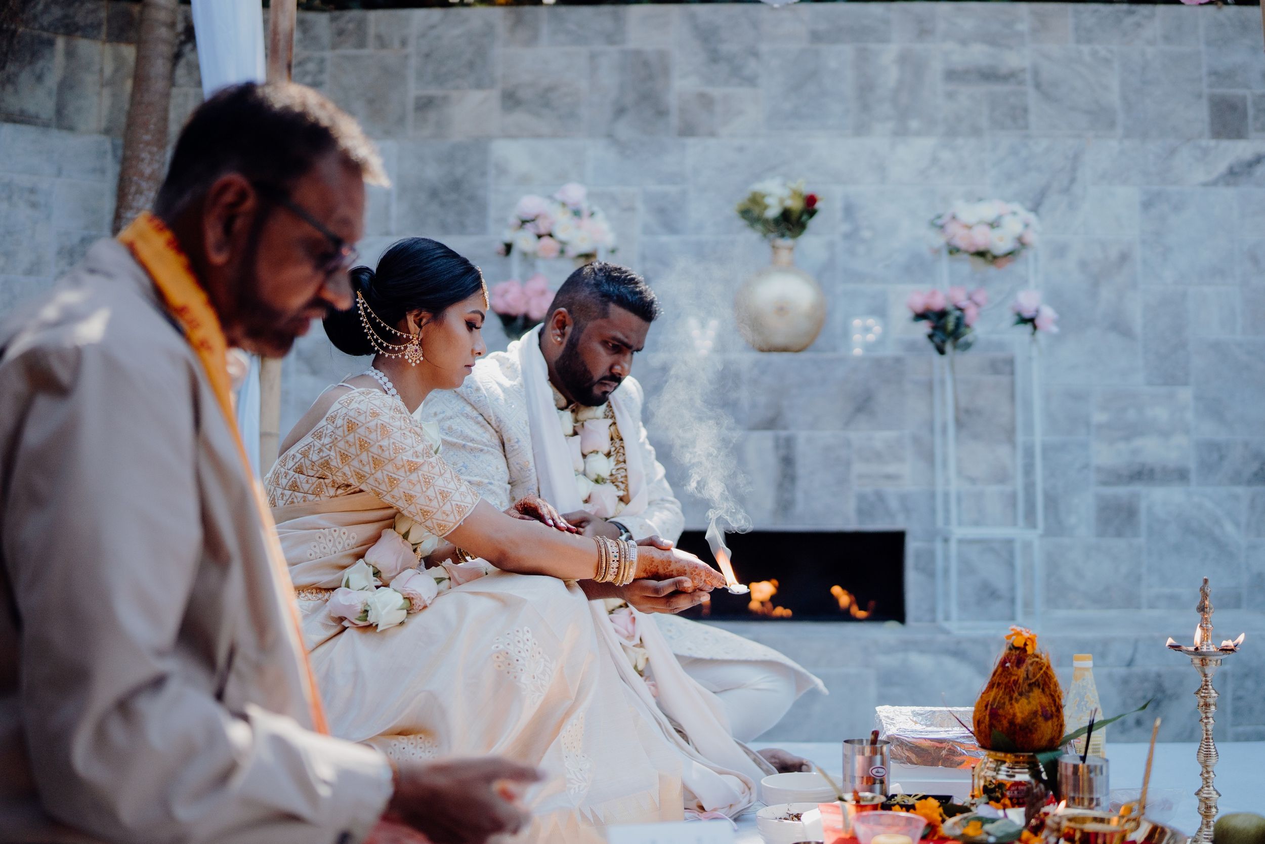 Traditional wedding ceremony participants perform rituals with candles and ceremonial items.