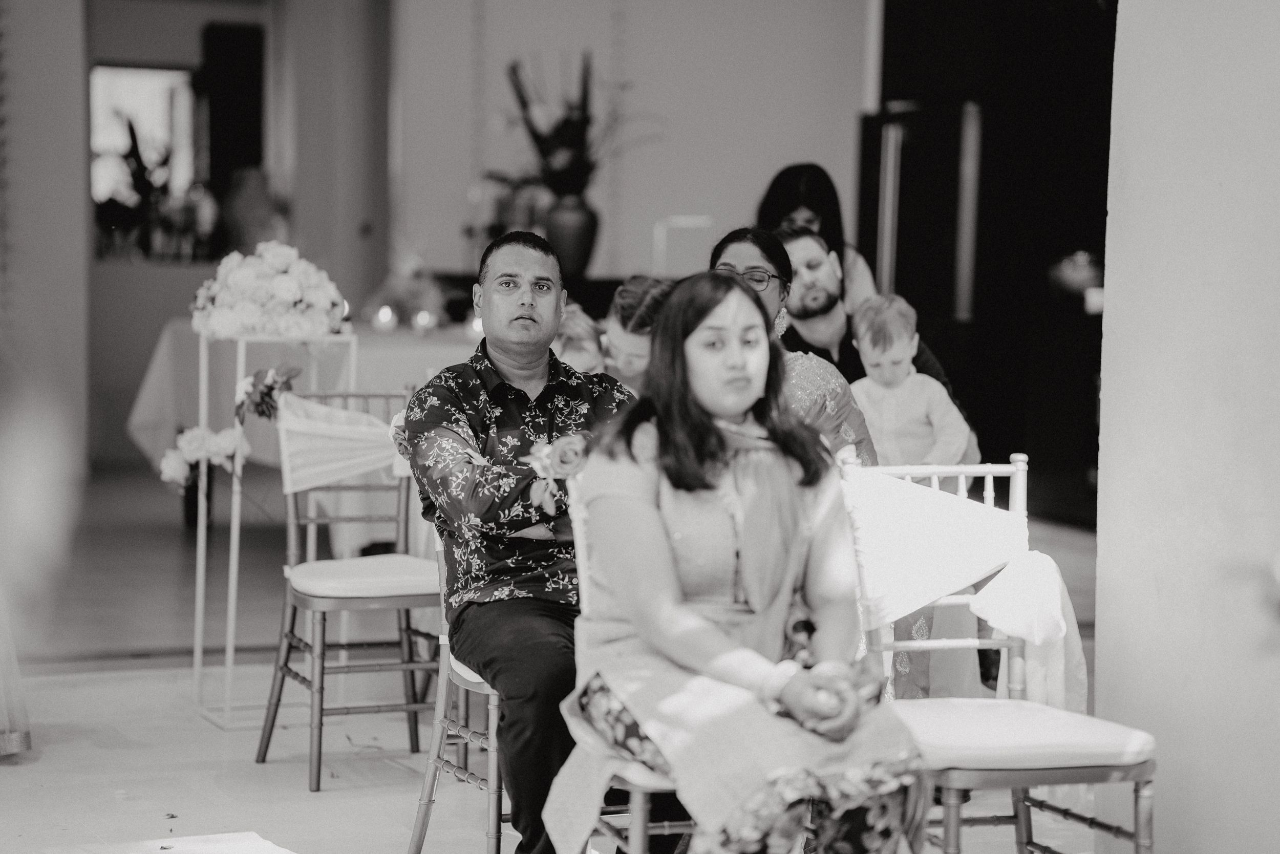 Black and white photo of guests seated at a formal indoor event.
