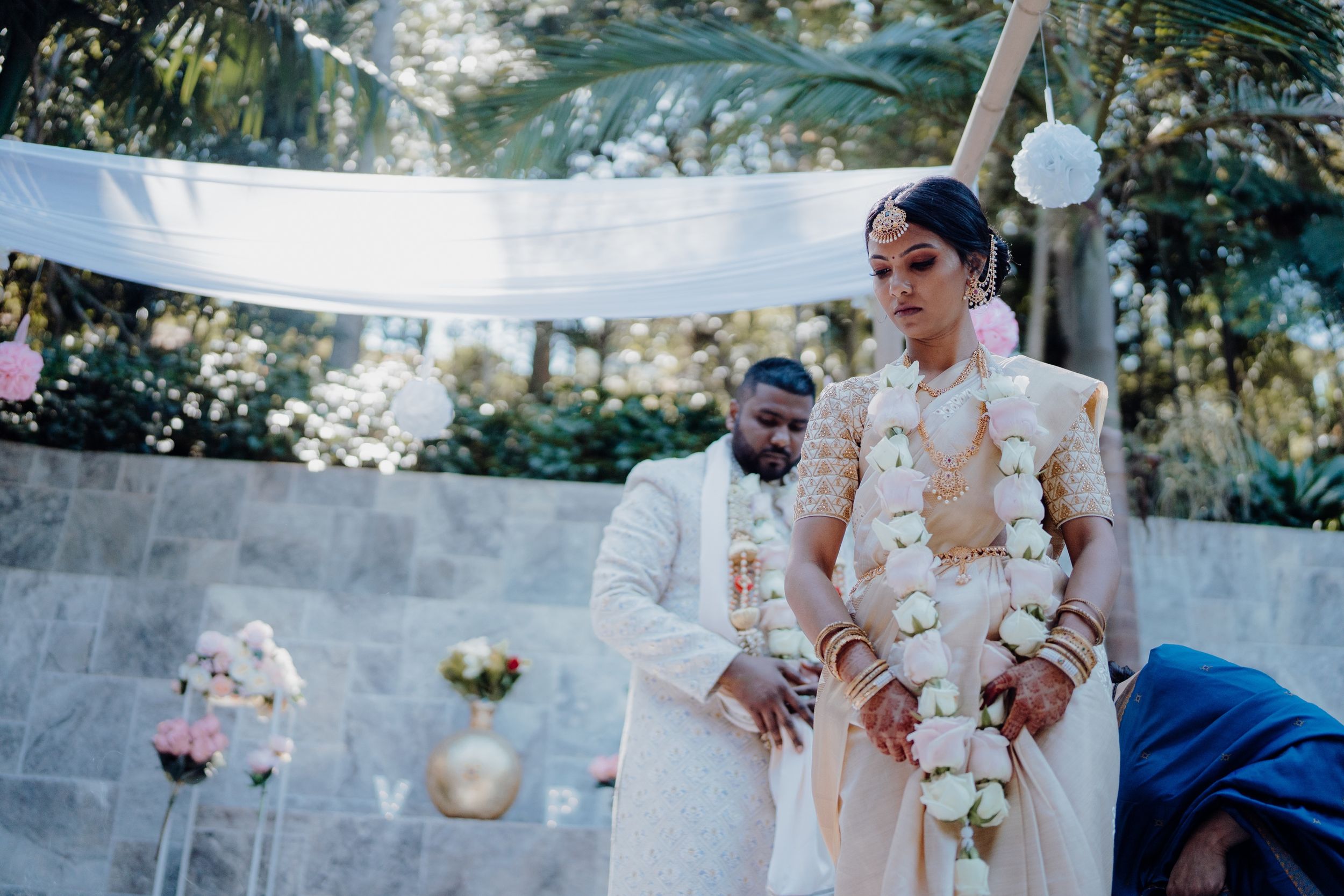 Outdoor wedding ceremony with elegant white decor and floral arrangements.