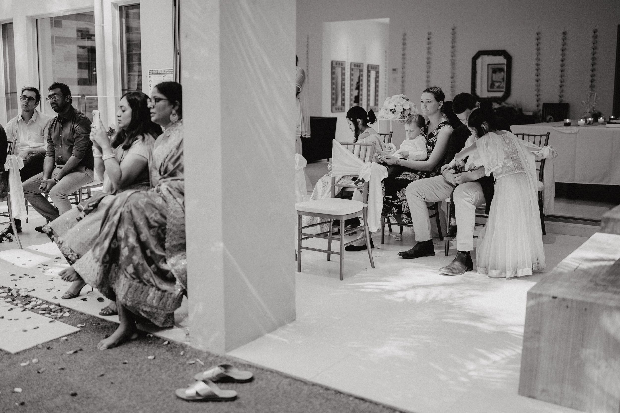 Black and white photo of guests seated and socializing at an indoor-outdoor venue.
