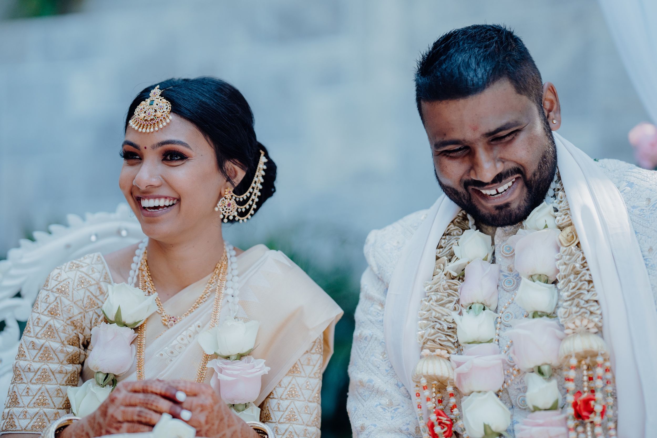 Couple in traditional Indian wedding attire sharing a joyful moment during ceremony.