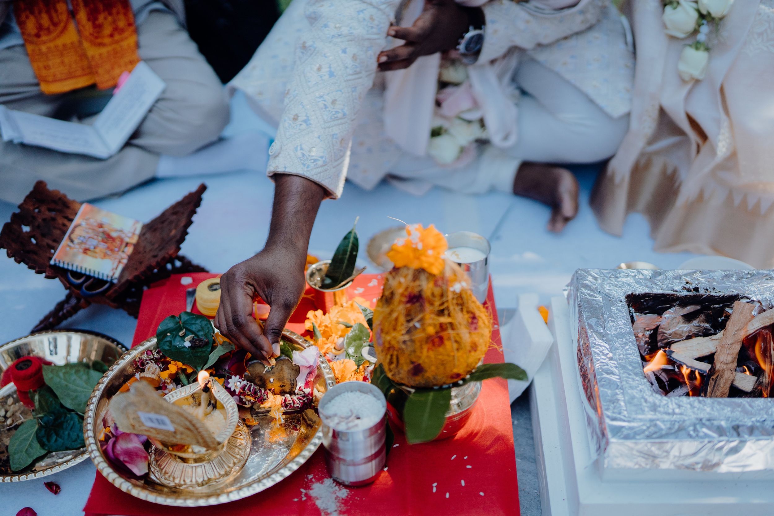 A festive wedding celebration table with colorful flowers and decorative items on a red tablecloth.