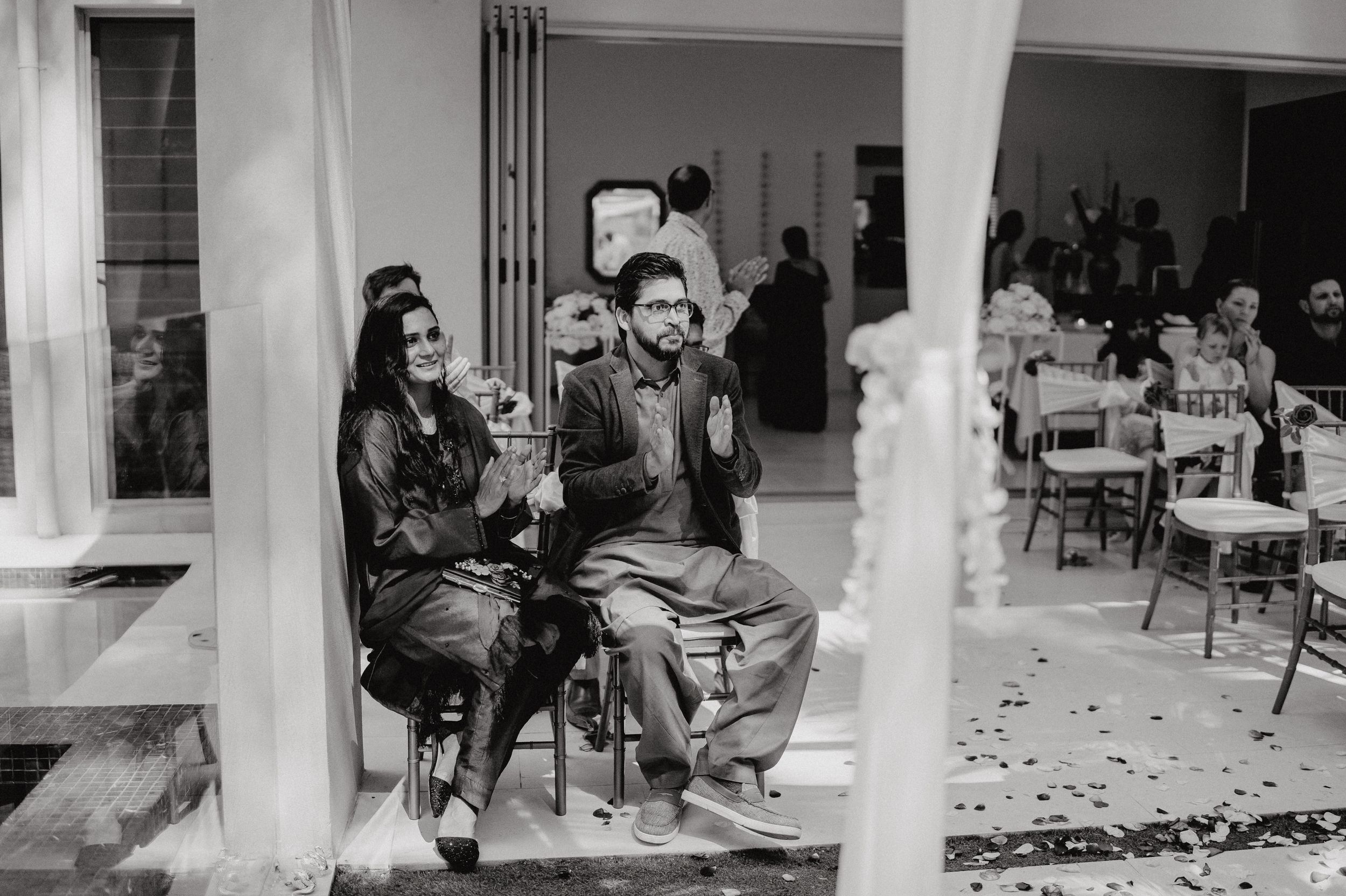 Black and white photo of guests seated at an outdoor wedding ceremony.