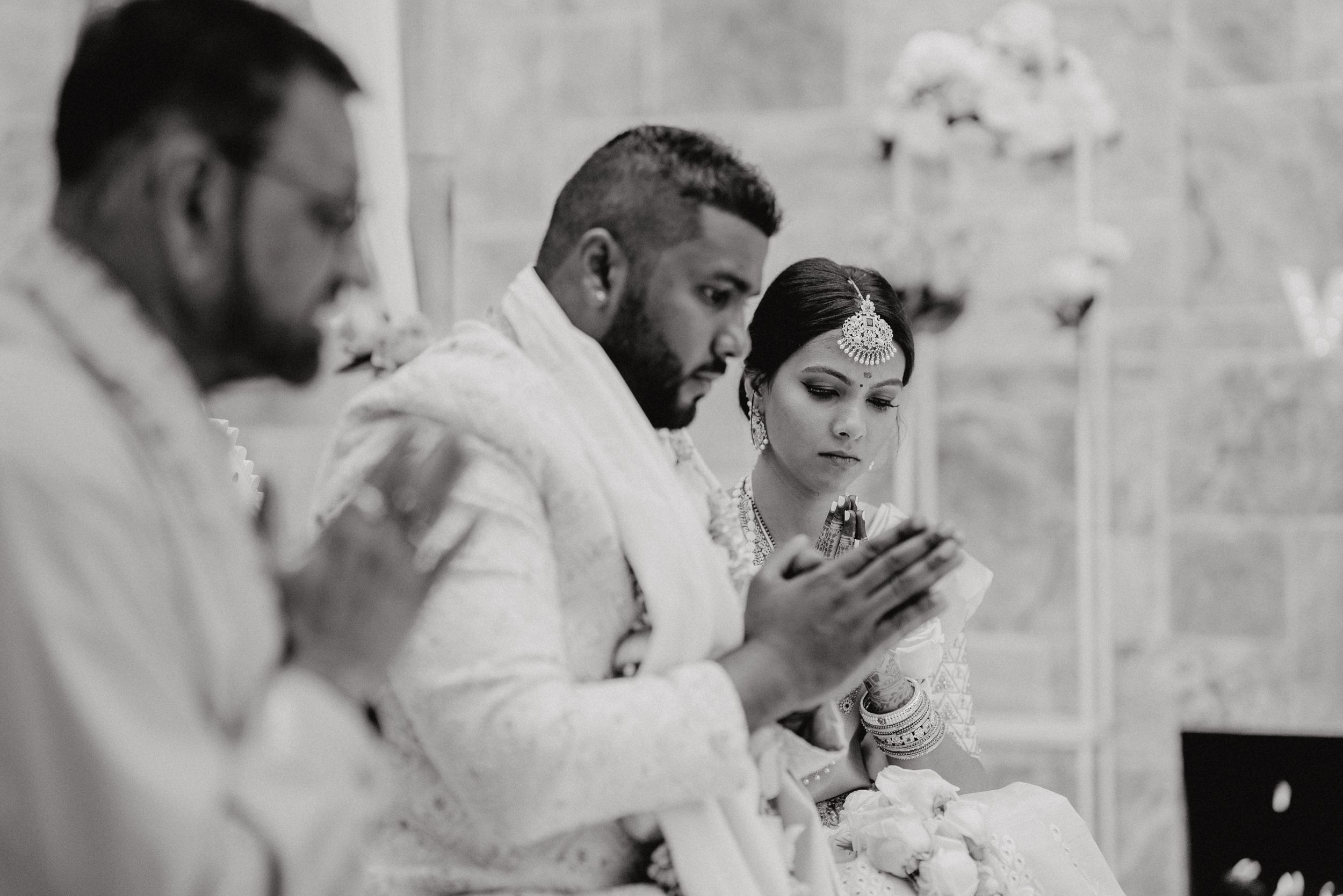 A black and white photo of people praying during a wedding ceremony.