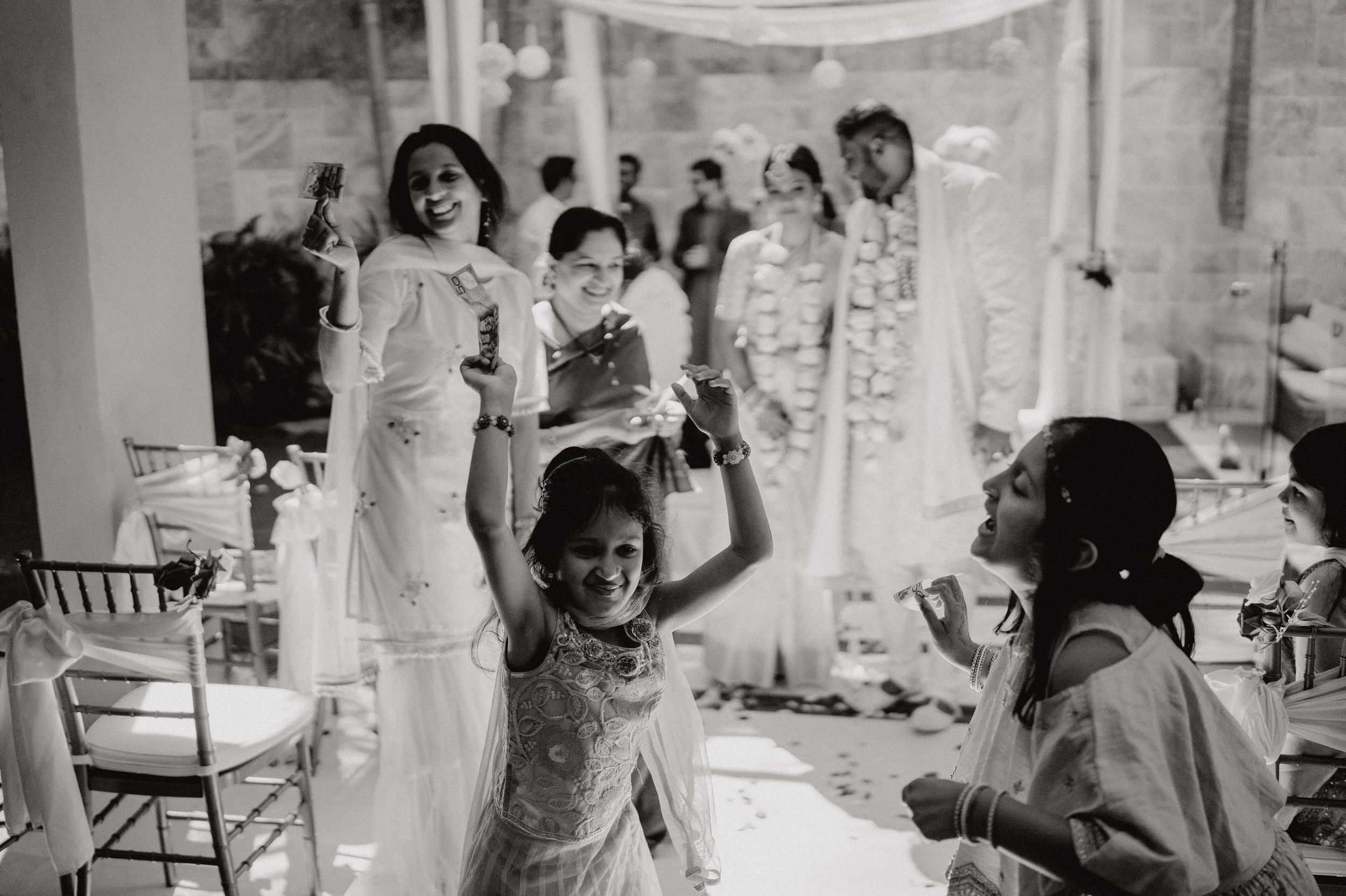 Black and white photo of wedding guests celebrating under draped fabric decor.