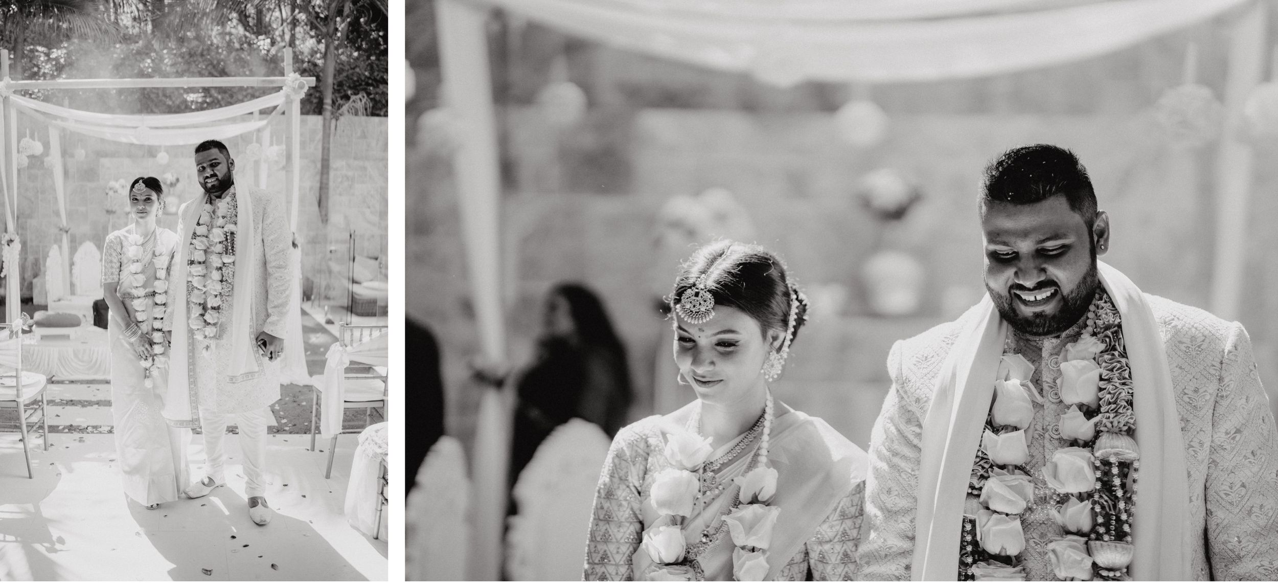 A couple wearing traditional garlands and wedding attire poses together at their ceremony.