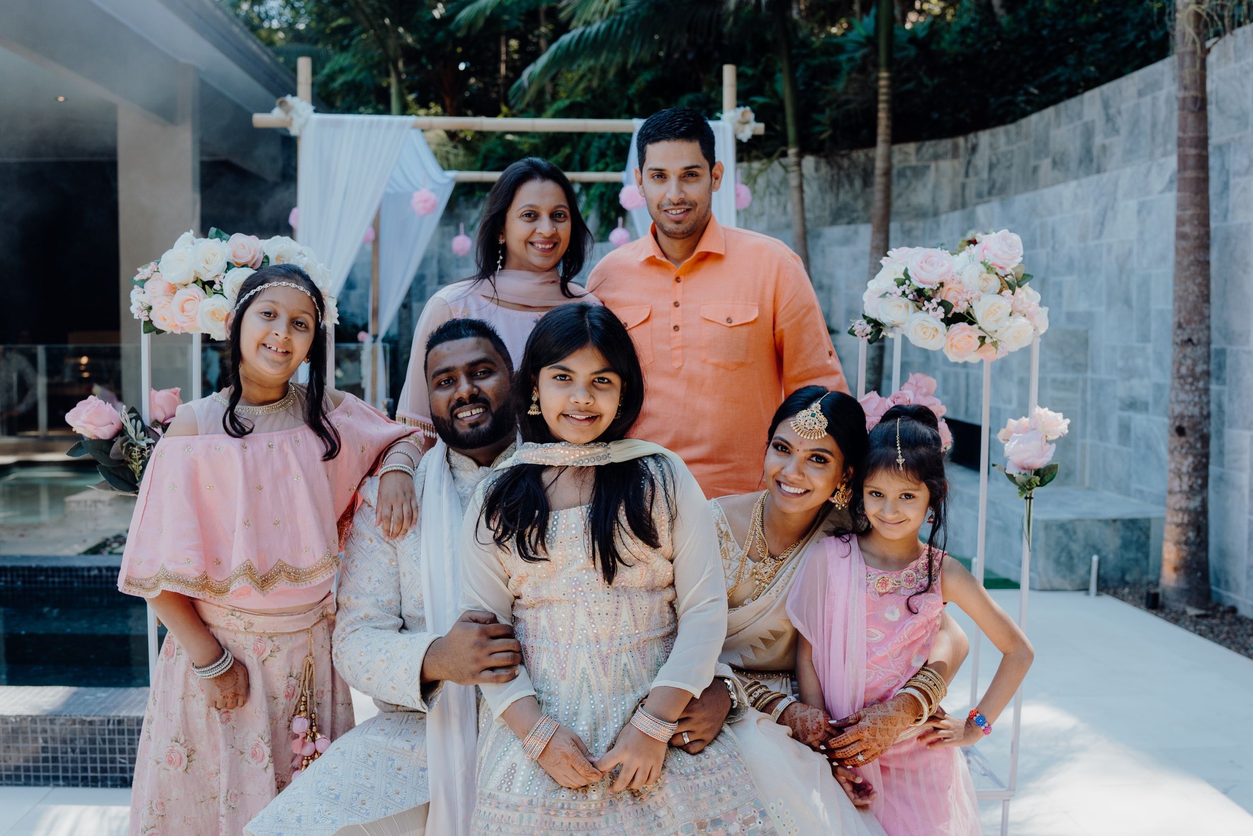 Family and friends gather for a wedding photo with pink floral decorations.