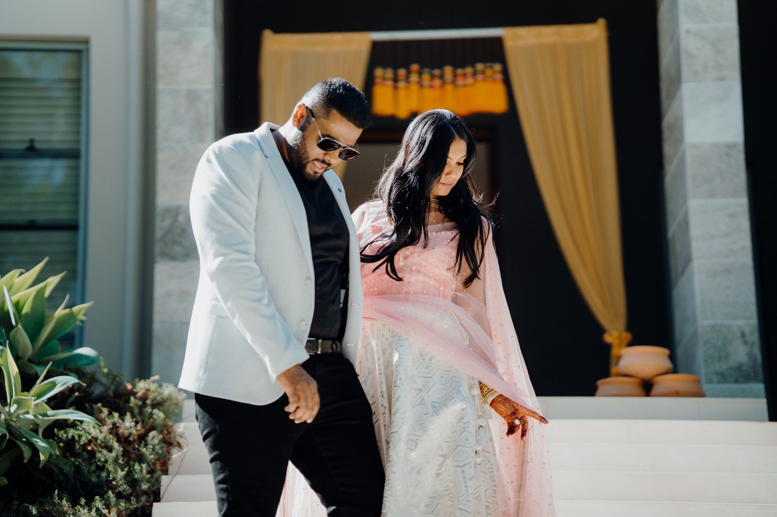 Couple sharing a joyful moment on their wedding day in front of golden curtains.