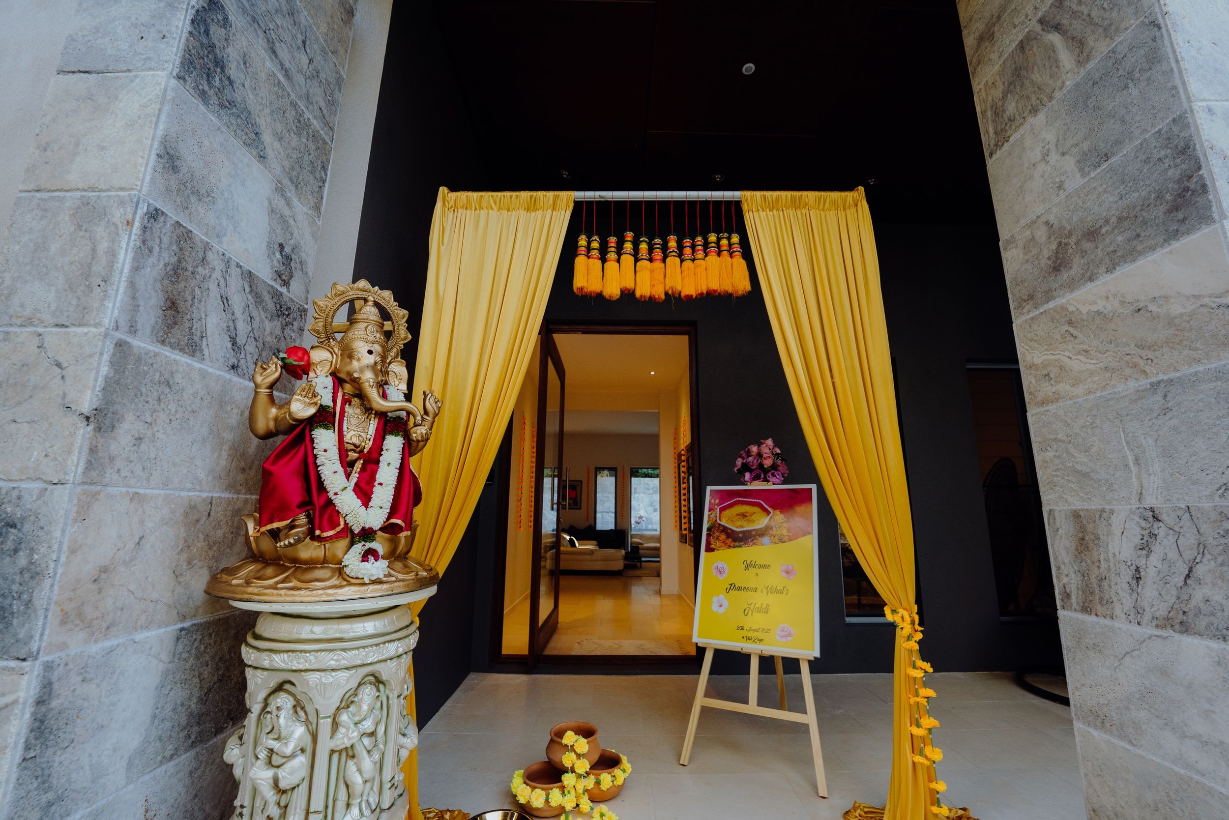 Yellow curtains frame an entrance with a traditional Indian deity statue and decorative elements.