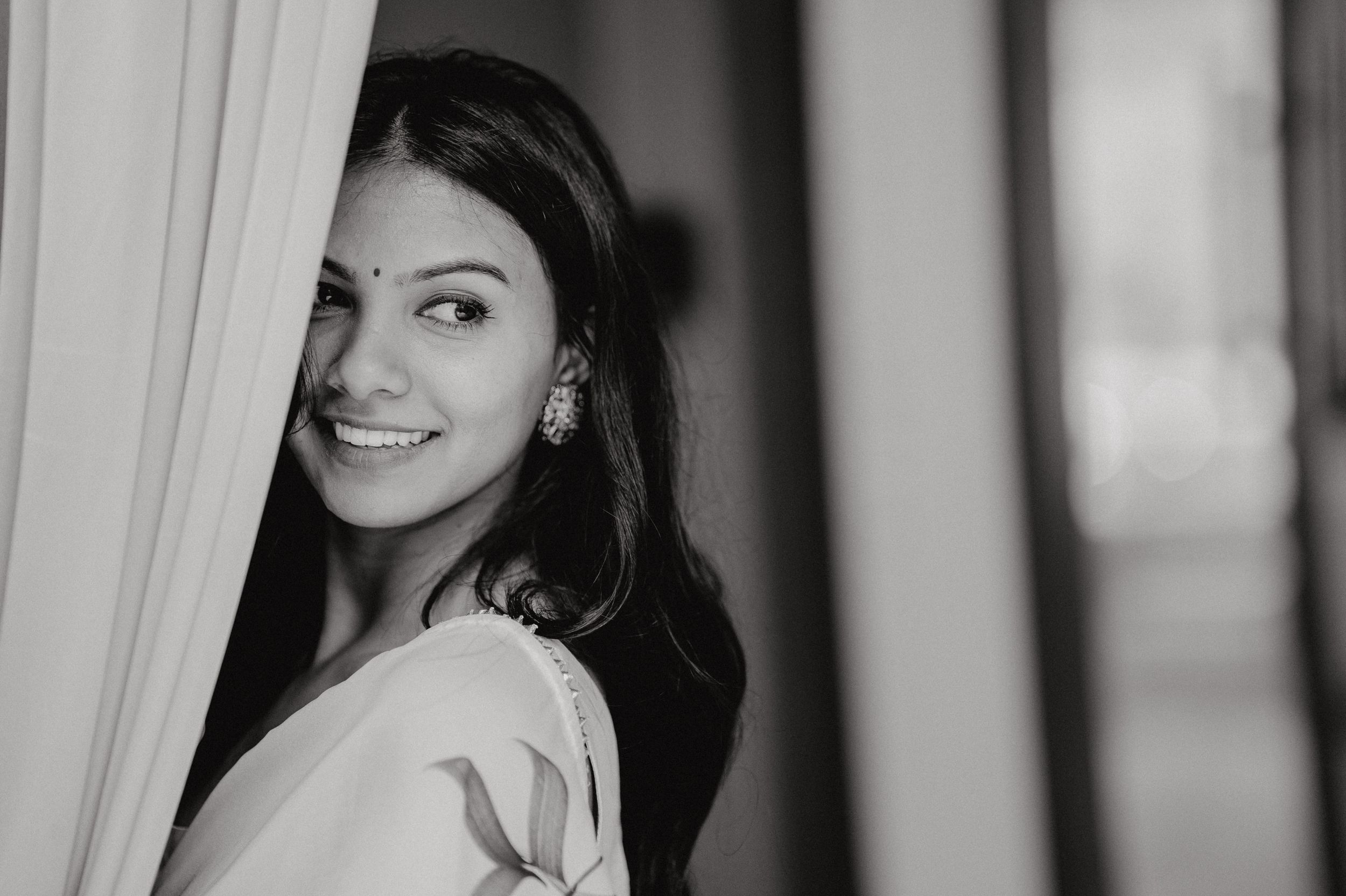 Black and white portrait shot with elegant curtain draping.