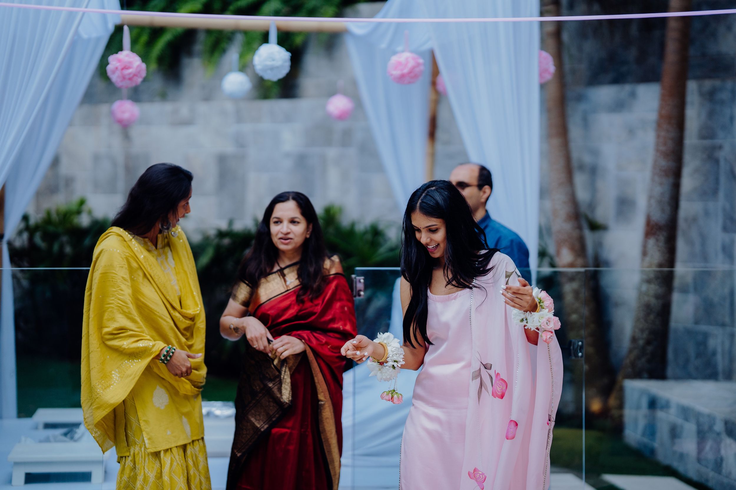 People in colorful traditional outfits socializing at an outdoor party with hanging decorations.
