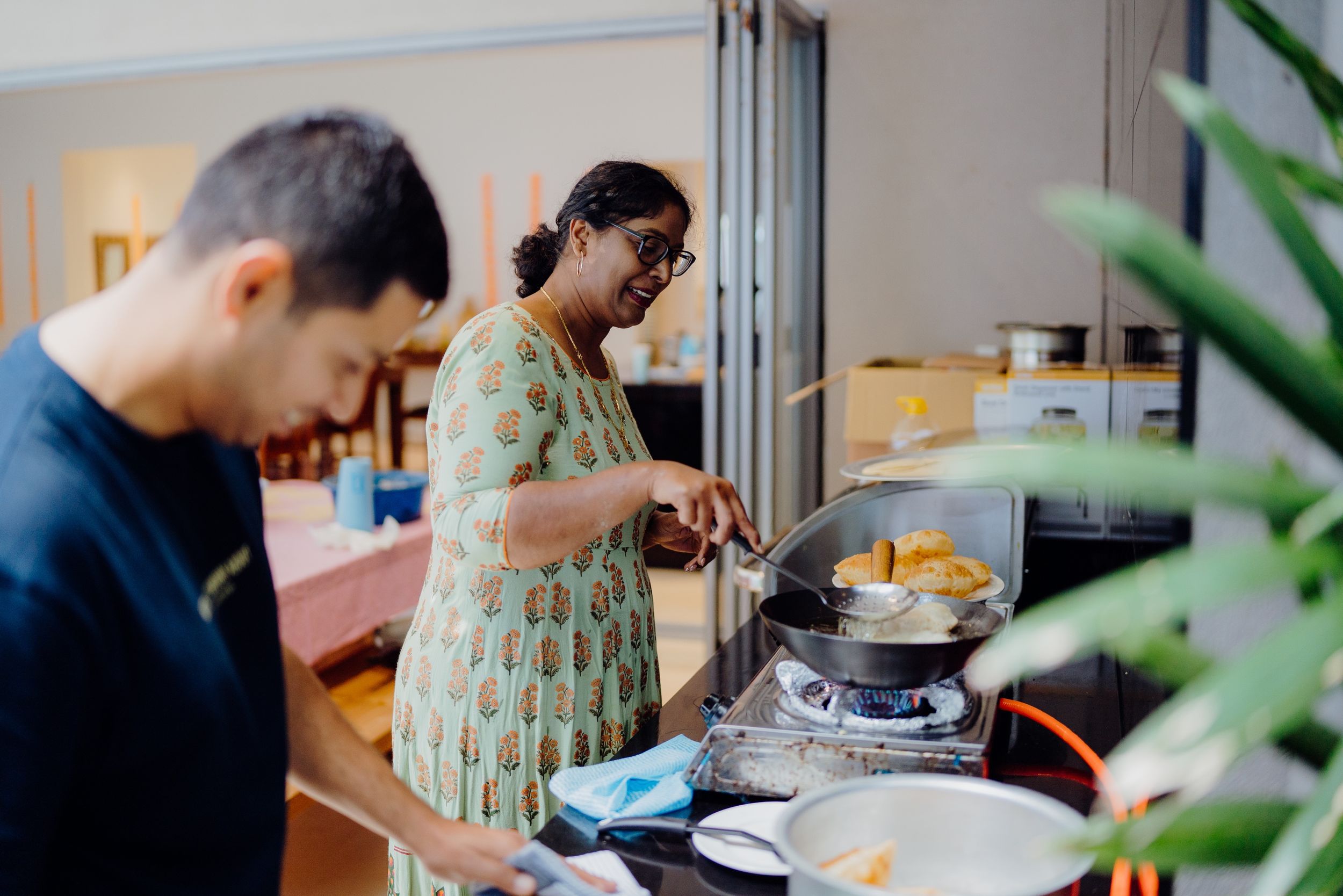 Two people preparing food in a modern kitchen with stainless steel appliances.