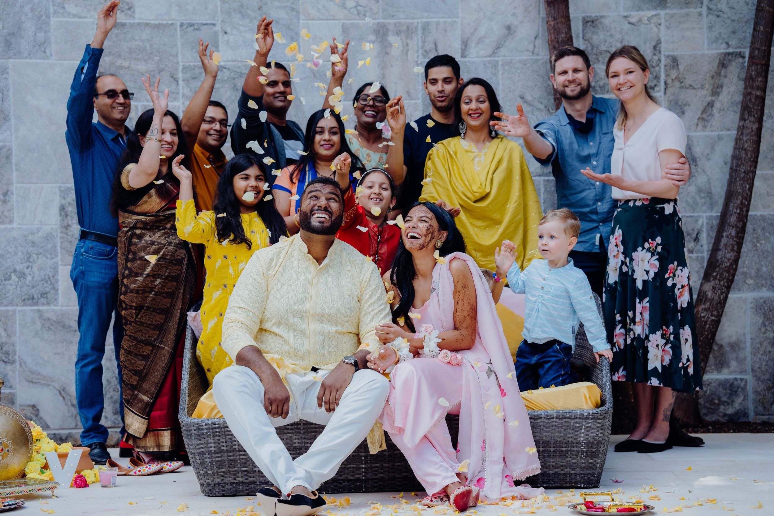 Large group in festive attire posing together for celebratory photo outdoors.