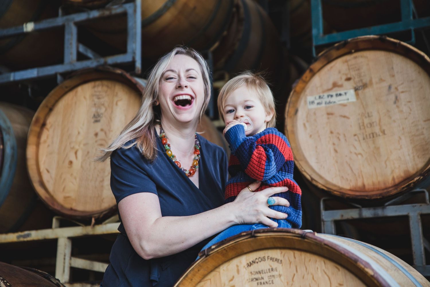 Winemaker laughing with her son at a winery in Santa Barbara Wine Country. Santa Maria Valley.