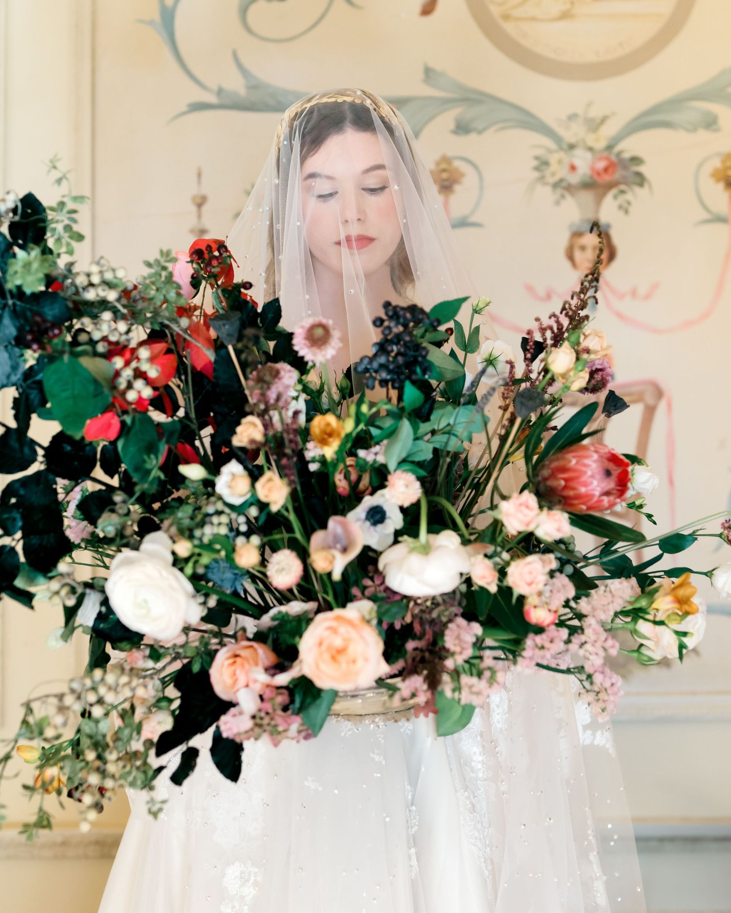Ethereal bridal scene with abundant colorful floral arrangements against decorative wallpaper.