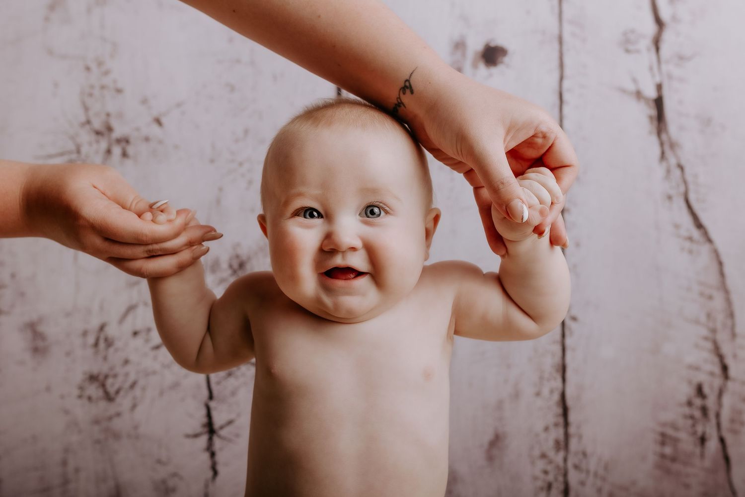 Baby enjoying bath time while splashing in vintage metal tub against rustic background.