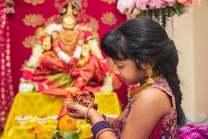Traditional Indian ceremony with decorated altar and deity in the background.