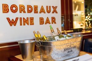 Bordeaux wine bar sign with illuminated letters and ice bucket of chilled bottles.