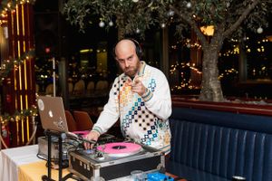 DJ performing with vinyl turntables and laptop at an upscale venue with ambient lighting.