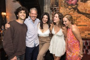 Group photo of friends and family gathered at a rustic brick-wall venue.