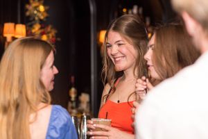 People laughing and socializing at a cozy bar with warm lighting.
