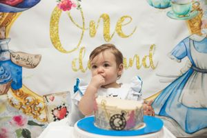 First birthday celebration with cake and Alice in Wonderland themed decorations.