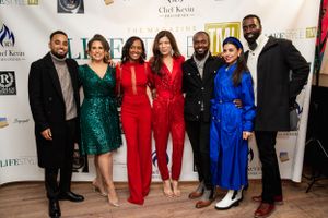 Group photo of people in formal attire at red carpet event.