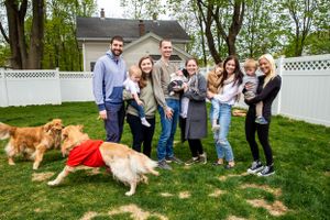 Extended family poses for a group photo with golden retrievers in a backyard.
