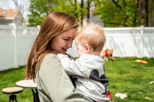 Tender moment shared between parent and child in backyard setting.