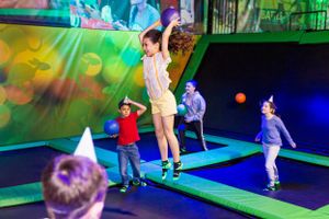 Kids jumping and playing at a trampoline park with colorful lighting effects.