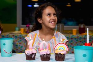 Rainbow-decorated cupcakes on a table at a birthday party celebration.