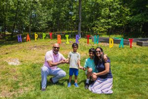 Family gathering in backyard with colorful letter decorations spelling happy birthday.