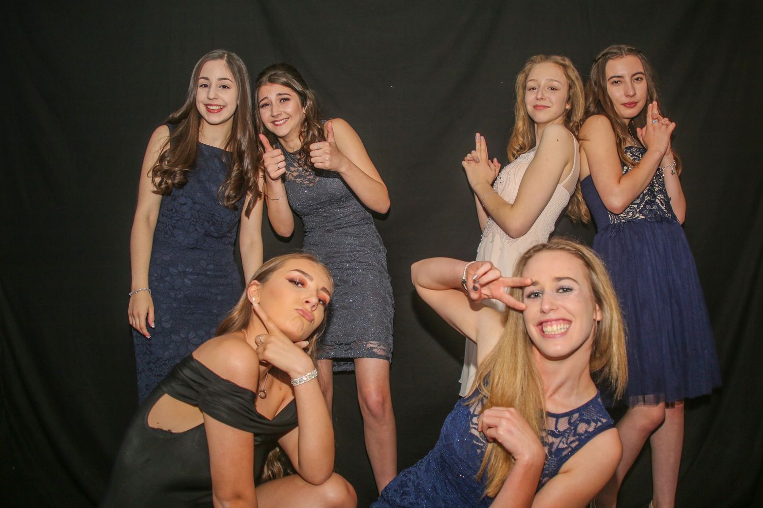 Group of friends posing together against a dark background in casual party attire.