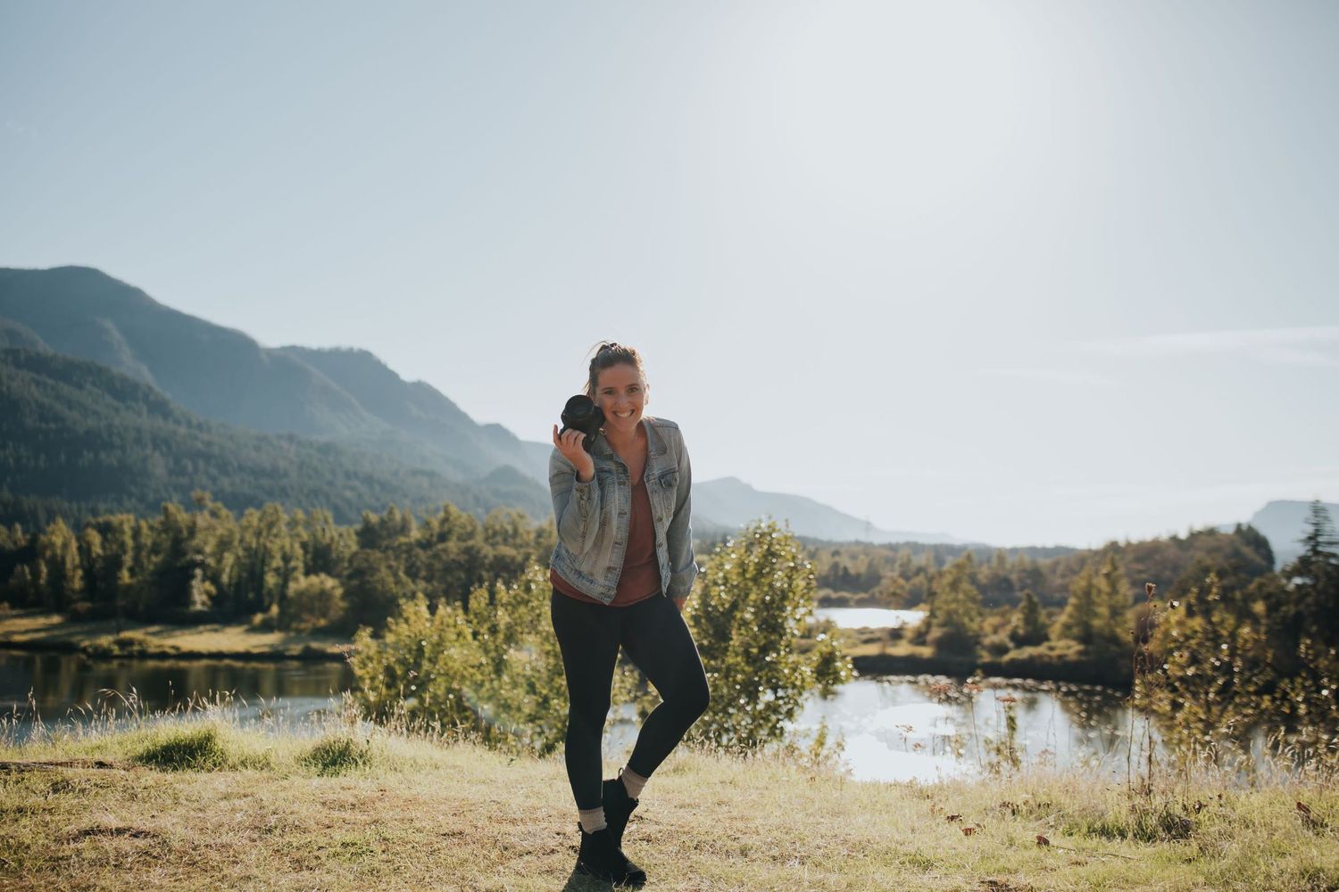 Oregon Wedding Photographer in front of lake holding camera