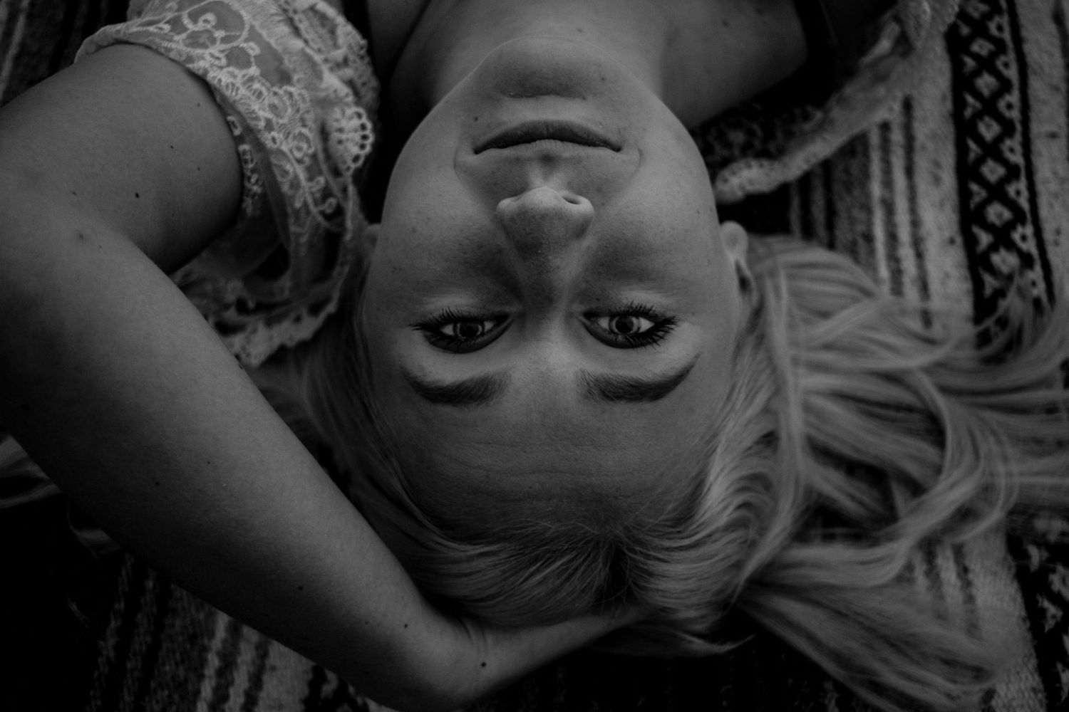 Artistic black and white portrait of someone laying upside down with long hair.