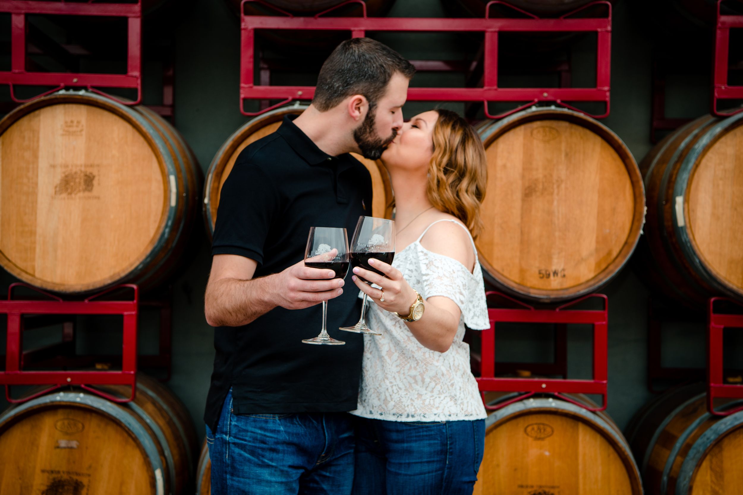 Romantic wine tasting moment between couple in front of oak barrels.