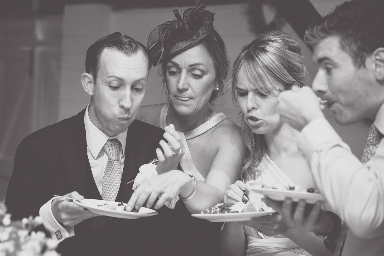 Wedding guests blow out candles on dessert plates at reception party.