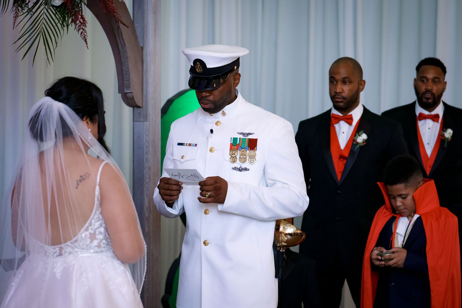 Military wedding ceremony with servicemember in white dress uniform reading vows.
