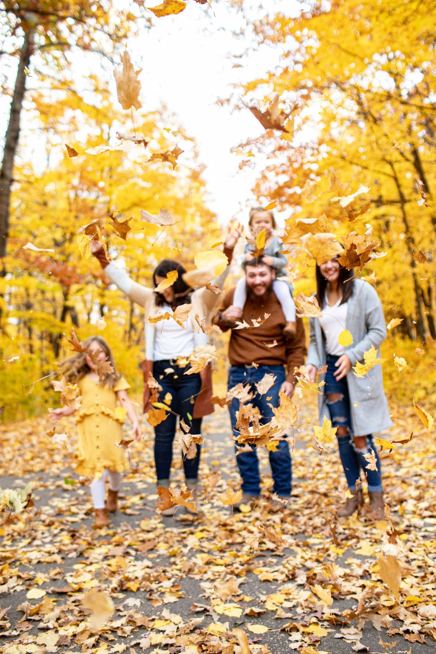 Family playing in colorful fall leaves during a photography session