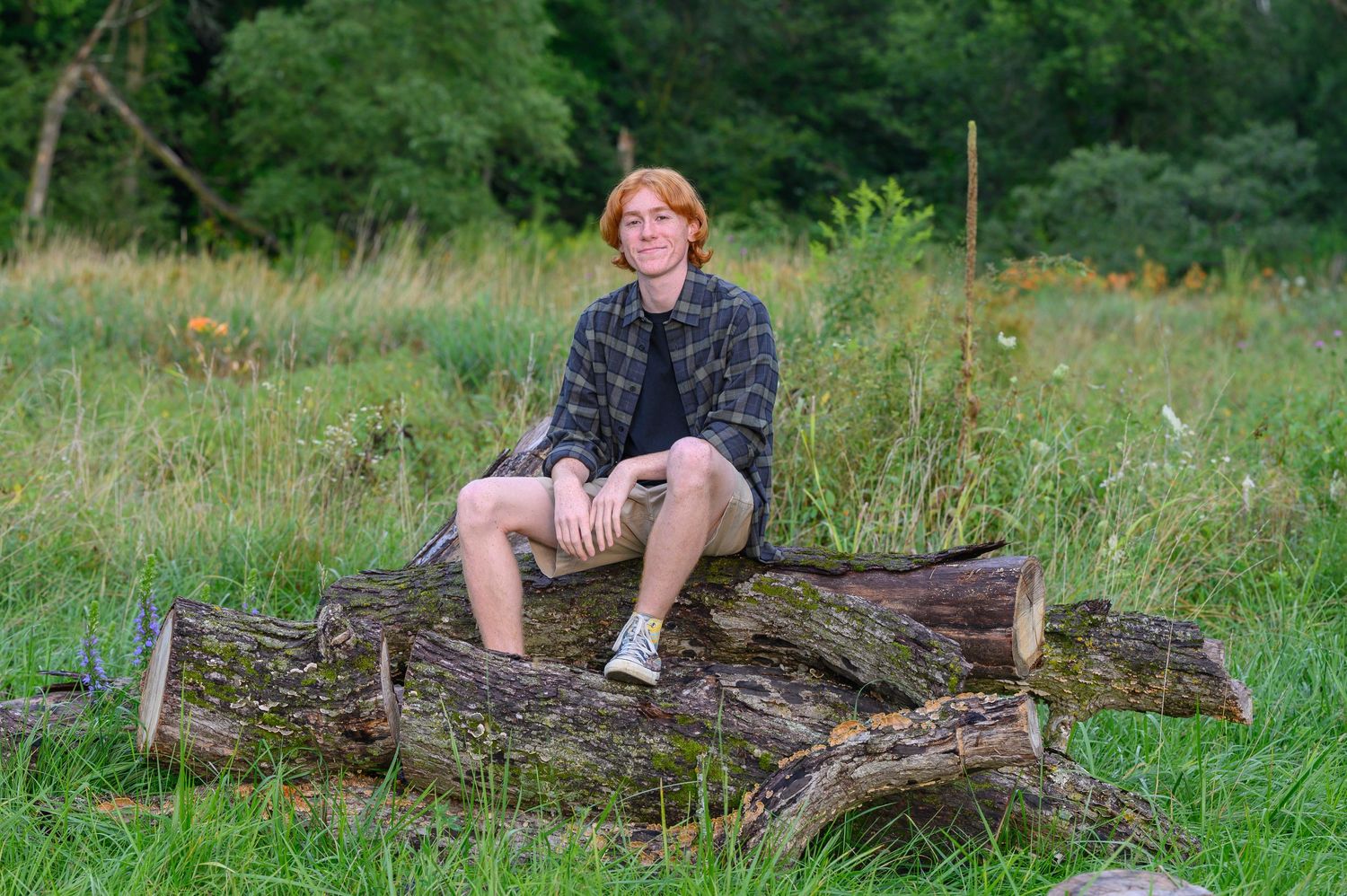 Senior Photo of Graduate Sitting on a pile of logs