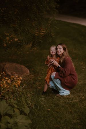A heartwarming outdoor scene with a parent and child sitting together among yellow wildflowers at sunset.