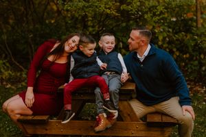 Happy family of four sitting together on a wooden picnic table during autumn.