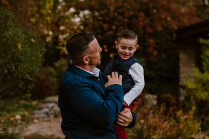A joyful moment shared between parent and child outdoors in fall foliage.
