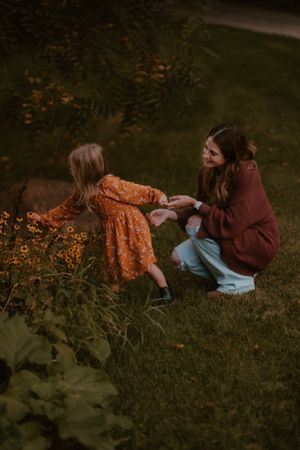 A tender moment captured outdoors as two people interact near blooming yellow flowers in a garden setting.