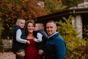 Family portrait outdoors featuring burgundy and navy outfits against autumn foliage.