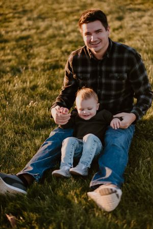 A sweet bonding moment captured on grass during golden hour.