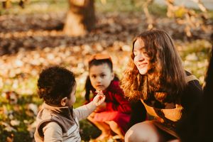 Group sharing joyful moments while sitting on autumn grass in golden sunlight.