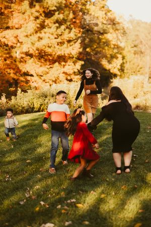 Family playing and dancing together on grass during golden hour.