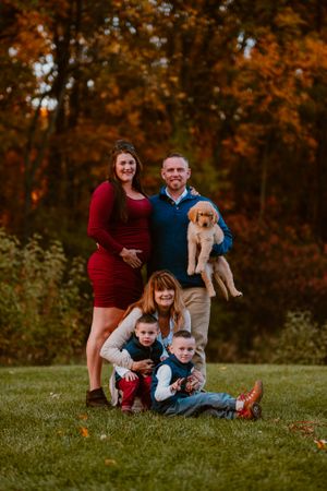 Family portrait with puppy in autumn setting with colorful fall foliage.