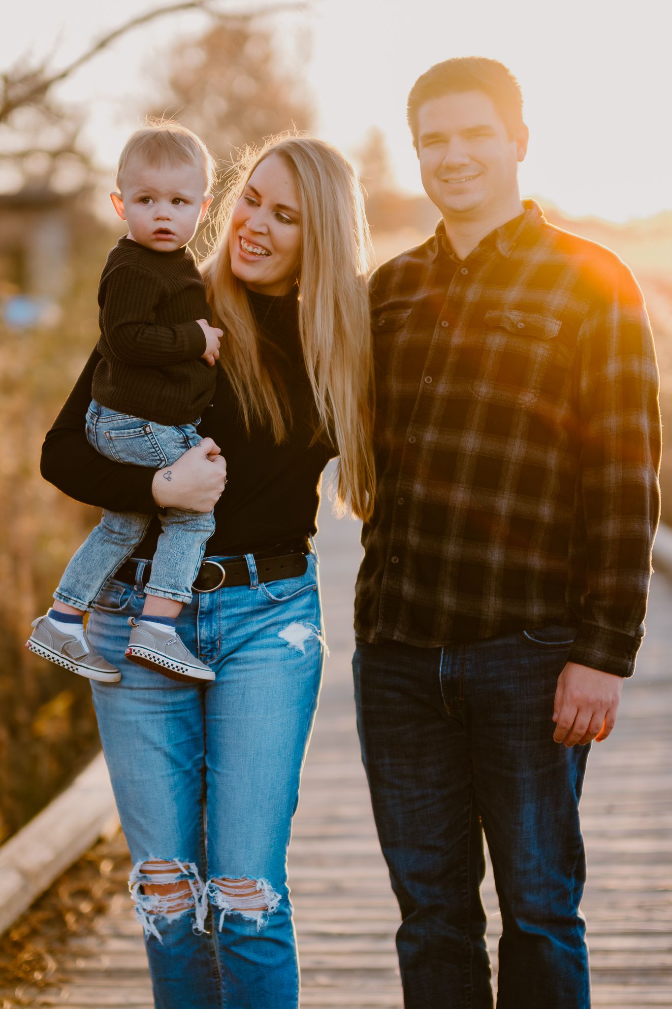 A casual family portrait on a wooden boardwalk during sunset.